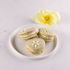 Peach & elderflower macarons with light green shells and white royal icing flower detail, part of the Mother’s Day macaron collection.